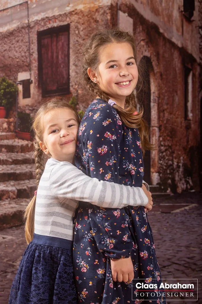 Zwei Schwestern umarmen sich im Fotostudio.